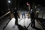 Julia Lindquist, 4, center, heads down the 5-meter ski jump as Erik Bakk-Hansen monitors the start of the kids practicing Tuesday, Jan. 18, 2022, at the Norge Ski Club in Fox River Grove, Ill. With the fearlessness befitting a 4-year-old, she shuffled her skis to the top of the 5-meter hill (16.4 feet) in between two wood posts and nudged herself down the run. (AP Photo/Charles Rex Arbogast)