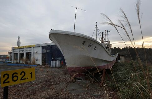 A fishing boat swept inland by a tsunami following the 2011 earthquake sits next to a bowling alley in an evacuation zone in Namie, Fukushima.