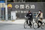Cyclists ride past a PetroChina Co. gas station in Shanghai.