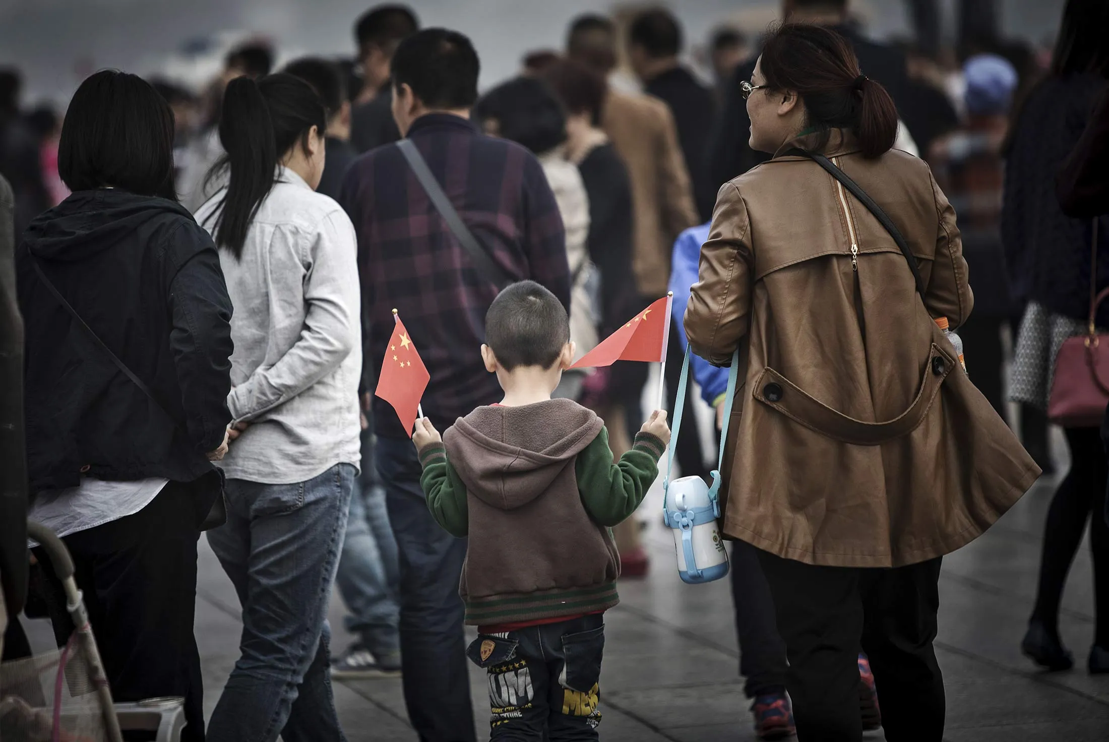 A child holding Chinese flags walks through Tiananmen Square in Beijing.
