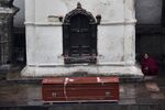 A Nepalese woman sits against a wall of the still-standing Pashupatinath Temple, facing an empty coffin after Kathmandu's devastating earthquake.