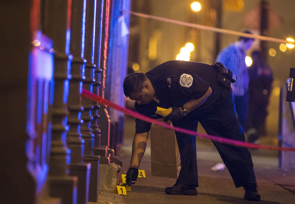 A Chicago police officer collects evidence from one of several shooting scenes over Fourth of July Weekend in 2015, when 9 people were killed in gun violence. 