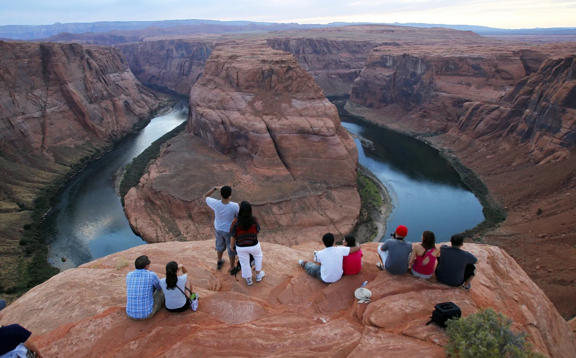 Visitors view the dramatic bend in the Colorado River at the popular Horseshoe Bend in Glen Canyon National Recreation Area, in Page, Ariz., on Sept. 9, 2011. Federal officials on Tuesday, Aug. 16, 2022, are expected to announce water cuts that would further reduce how much Colorado River water some users in the seven U.S. states reliant on the river and Mexico receive. (AP Photo/Ross D. Franklin, File)