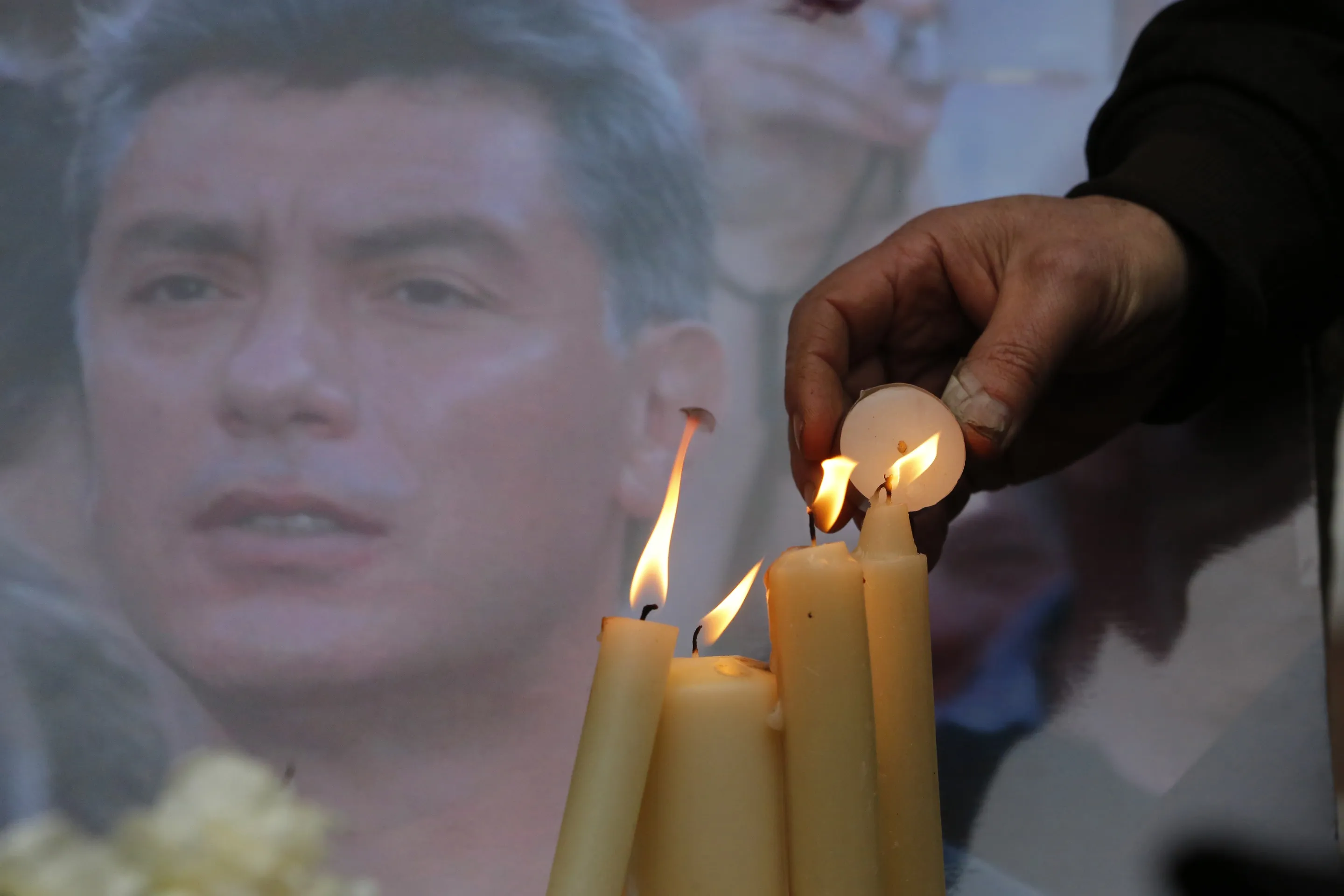 People light candles in memory of Boris Nemtsov, seen behind, at the monument of political prisoners 'Solovetsky Stone' in central St.Petersburg, Russia.
