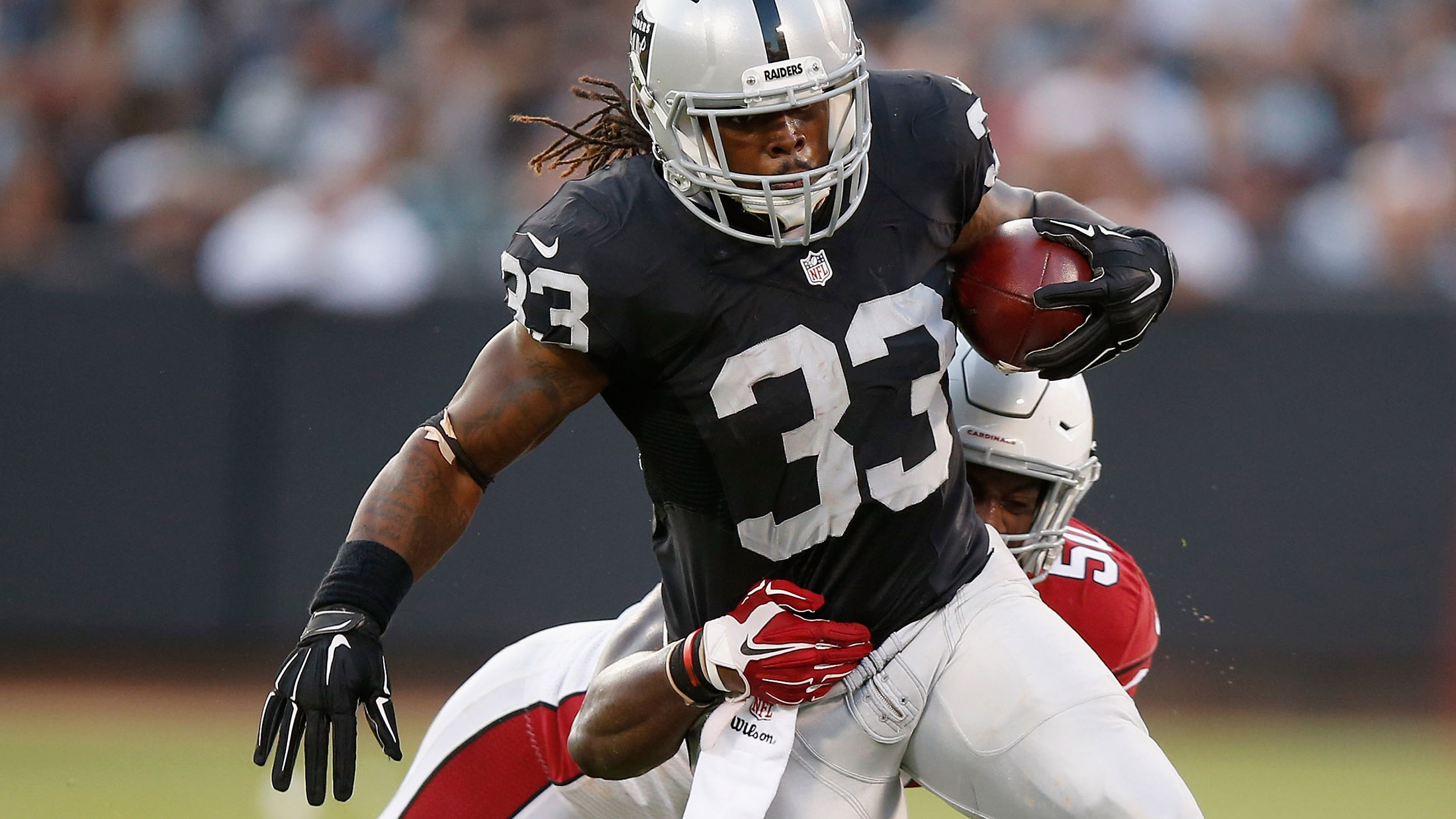 Trent Richardson #33 of the Oakland Raiders is tackled by Gabe Martin #50 of the Arizona Cardinals at O.co Coliseum on August 30, 2015 in Oakland, California.

