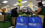 Reusable shopping bags hang as a cashier checks out customers during the grand opening of a Wal-Mart Stores Inc. location in the Chinatown neighborhood of Los Angeles, California, U.S., on Thursday, Sept. 19, 2013. 