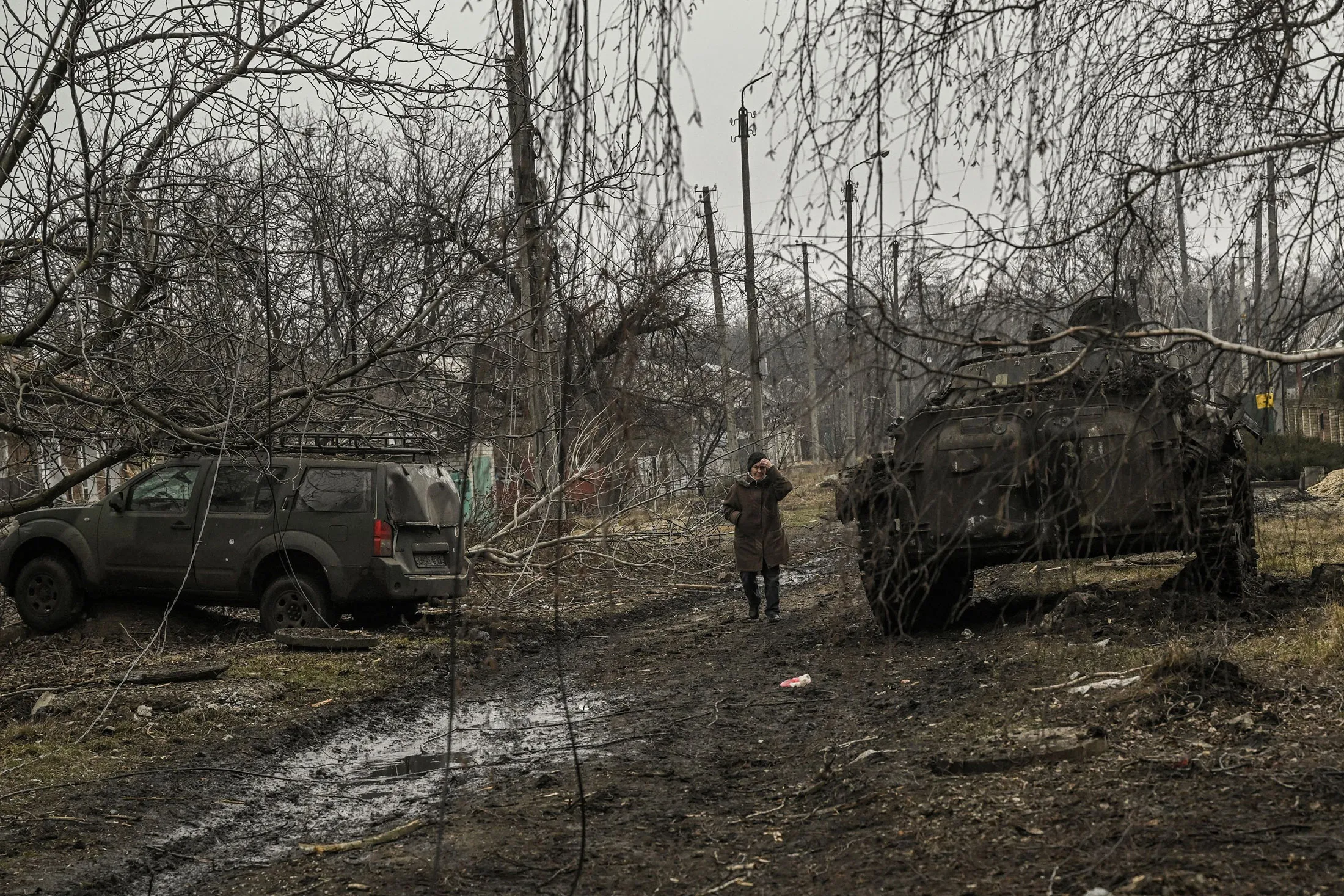 A woman walks past between a damaged military vehicle and a destroyed BMP-2 tank after a shelling in the village of Chasiv Yar, Ukraine, on March 11.
