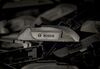Automobile windshield wiper blade arm fittings sit on the assembly line at a Robert Bosch plant.