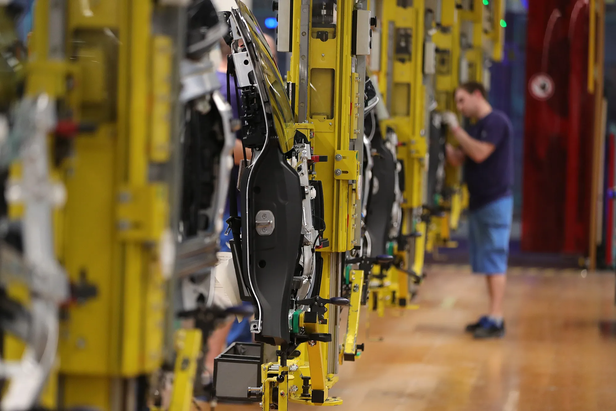 Employees fit doors on automobiles at a factory in Leipzig.