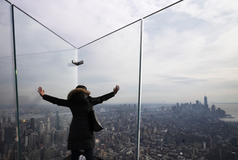 A woman looks out over Manhattan from an observation deck at the top of a tower in Hudson Yards.