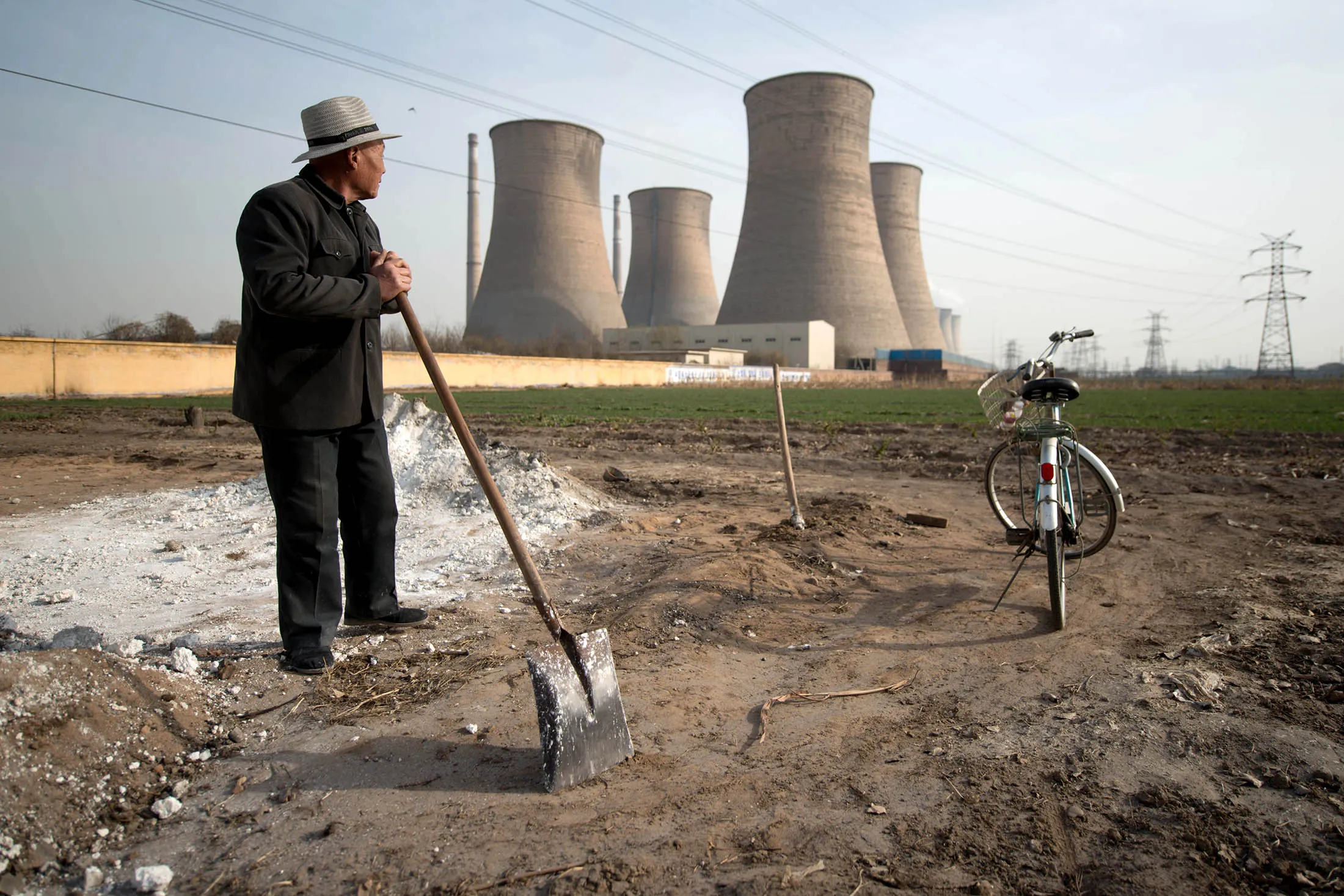 A man looks towards chimney stacks in a field outside a power plant in Xingtai.

