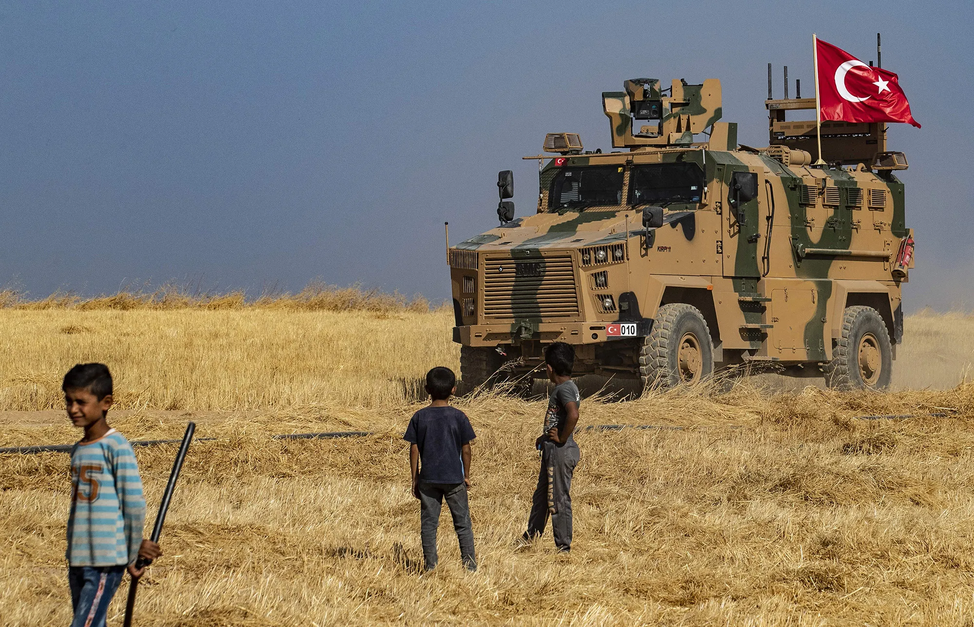 Syrian boys watch as a Turkish military vehicle patrol on Oct.&nbsp;4.