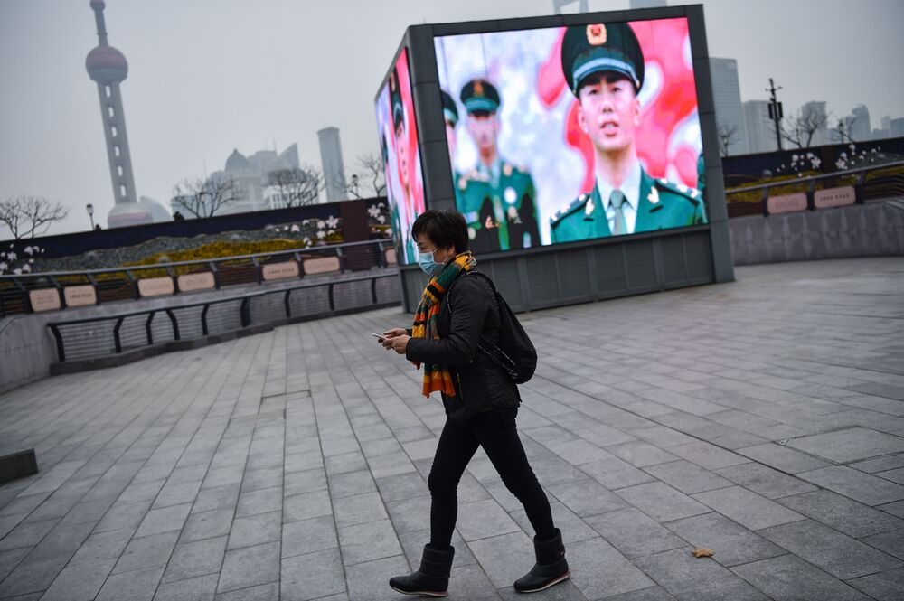 A woman wearing a protective mask walks to the promenade of the Bund along the Huangpu River in Shanghai on January 21, 2020. 