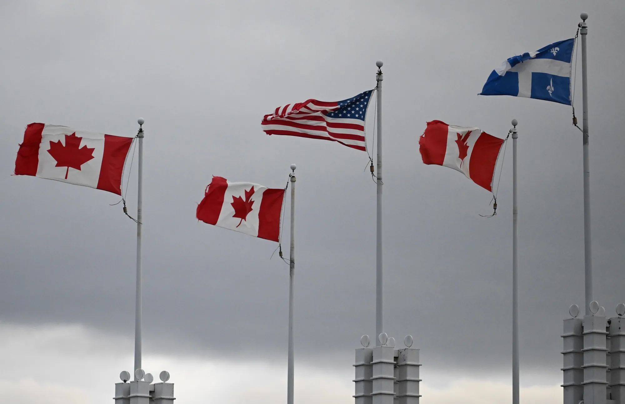 Canadian, American and Quebec flags at the Canada-US border in St-Bernard-de-Lacolle, Quebec, Canada.