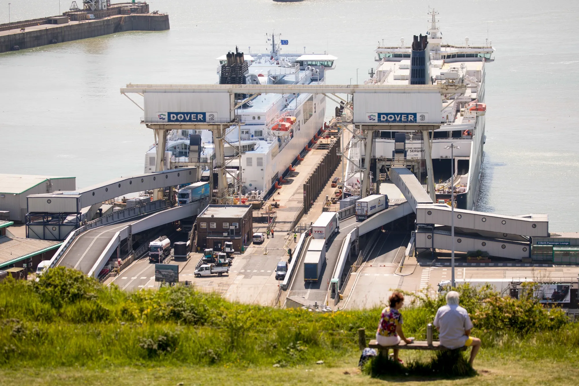 A couple sit on a bench of in view of ferries loading and unloading trucks at the Port of Dover Ltd. in Dover, U.K., on May 27.