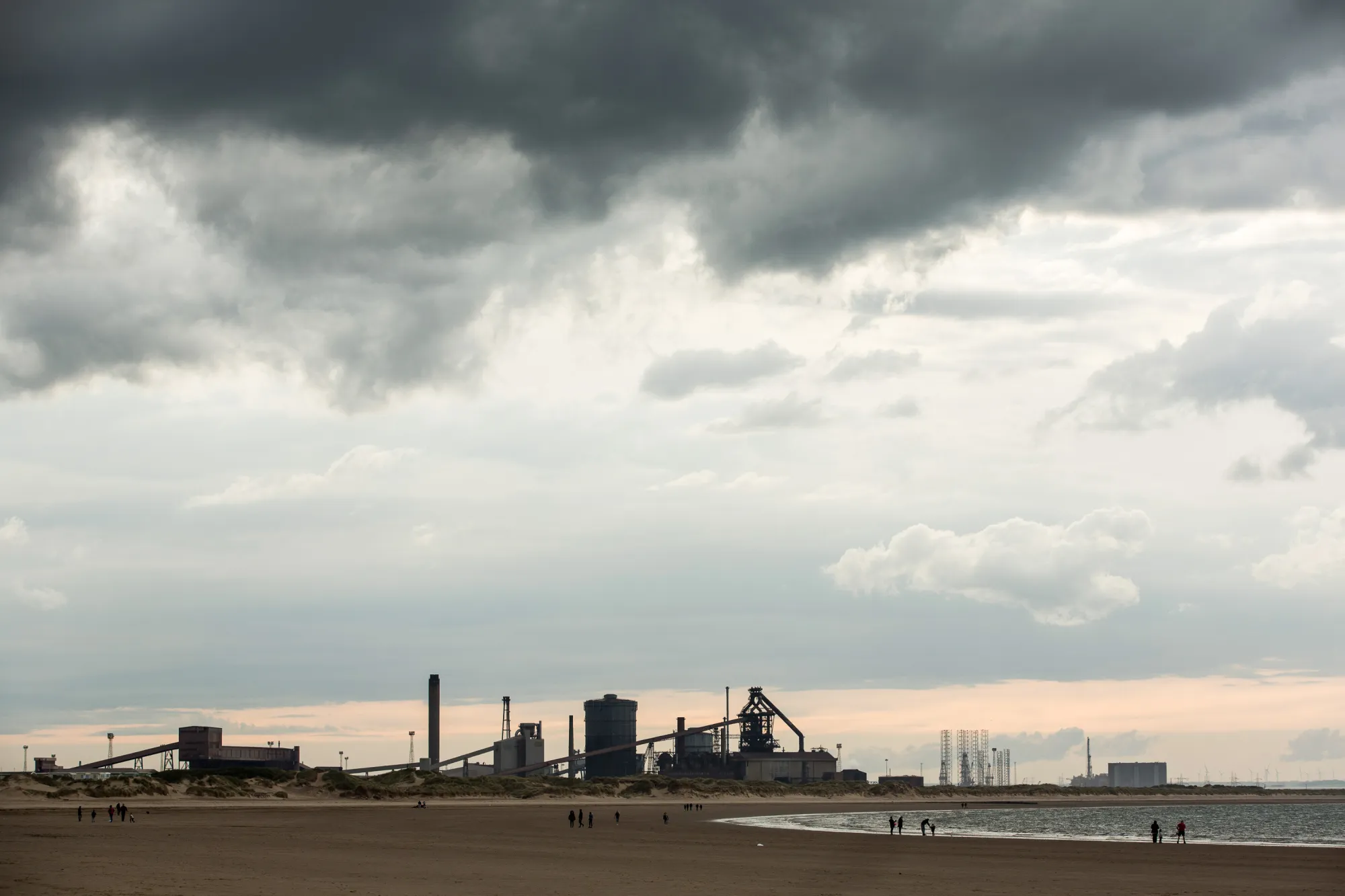 Families play on the beach in front of the shuttered Teesside Steelworks in Redcar.
