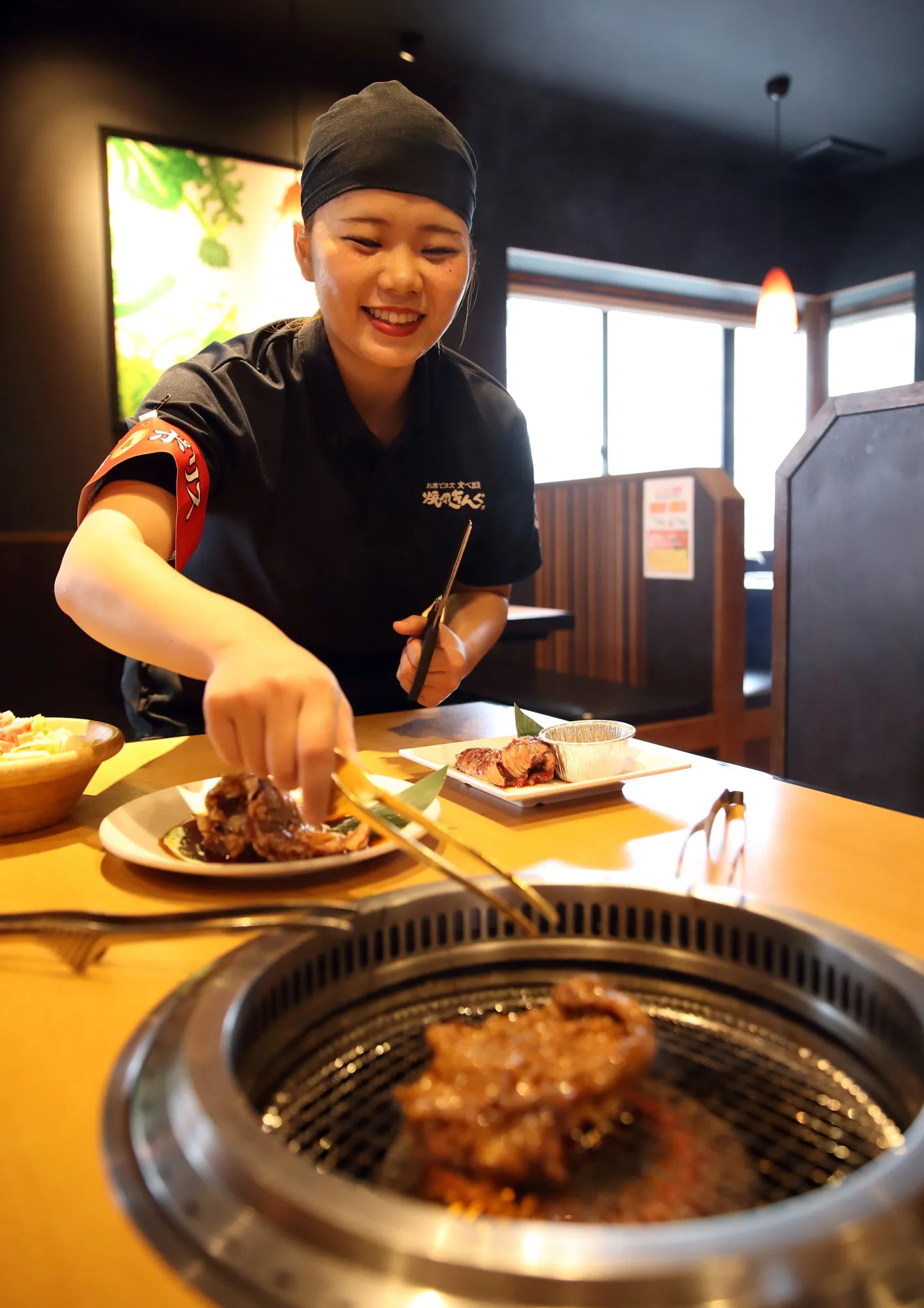 An employee grills a piece of meat at Yakiniku King restaurant.