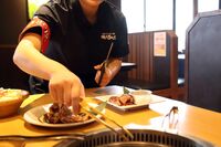 An employee grills a piece of meat at Yakiniku King restaurant.