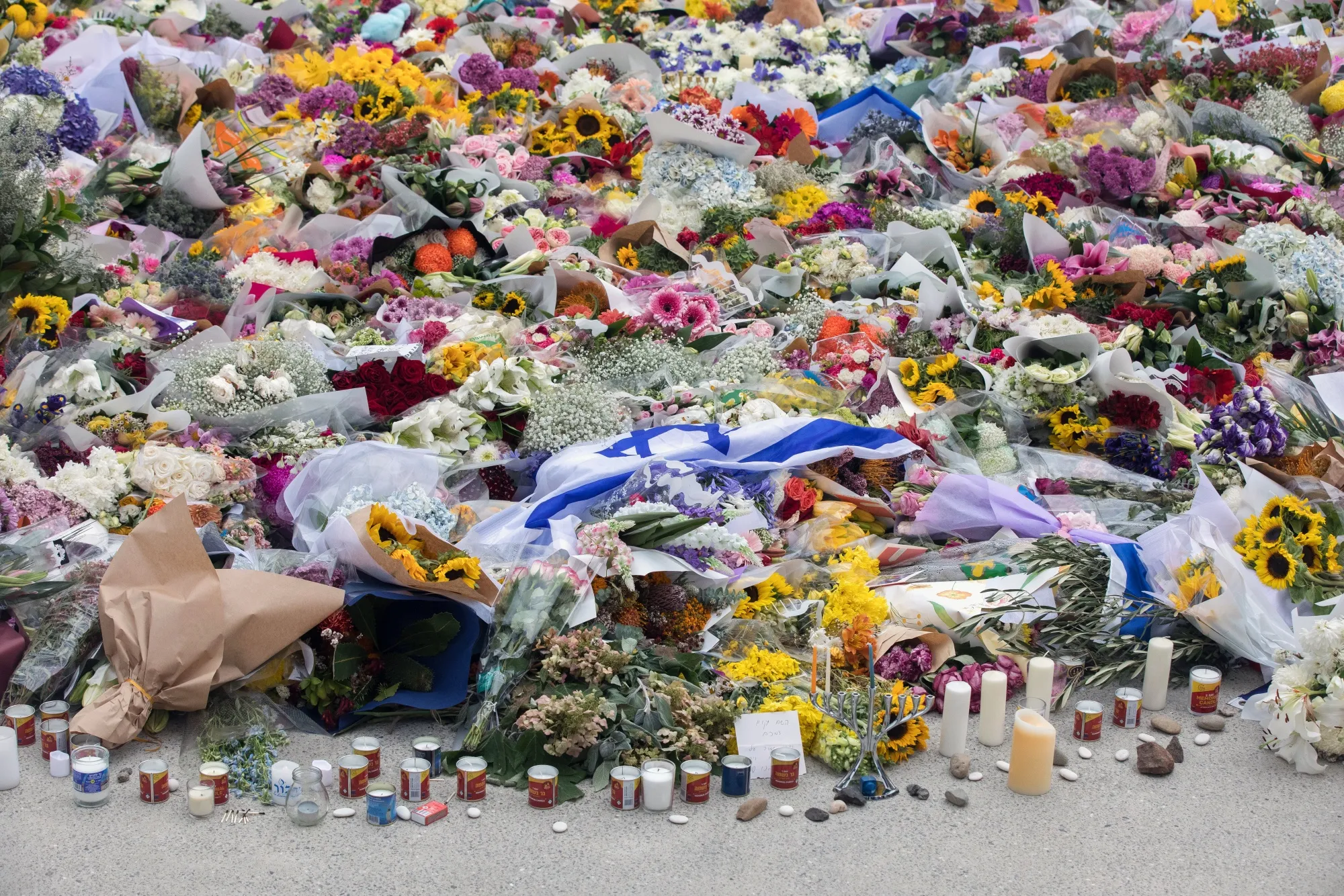Flowers and candles placed near the site of the mass shooting at Bondi Beach yesterday.