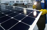 An employee of SunPower Corp. trims the edges and checks solar panels at the SunPower Corp.