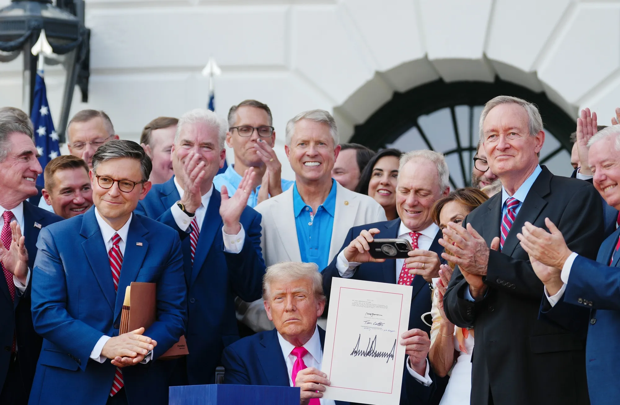US President Donald Trump displays the signed bill during a ceremony for the One Big Beautiful Bill Act on the South Lawn of the White House on July 4, 2025.