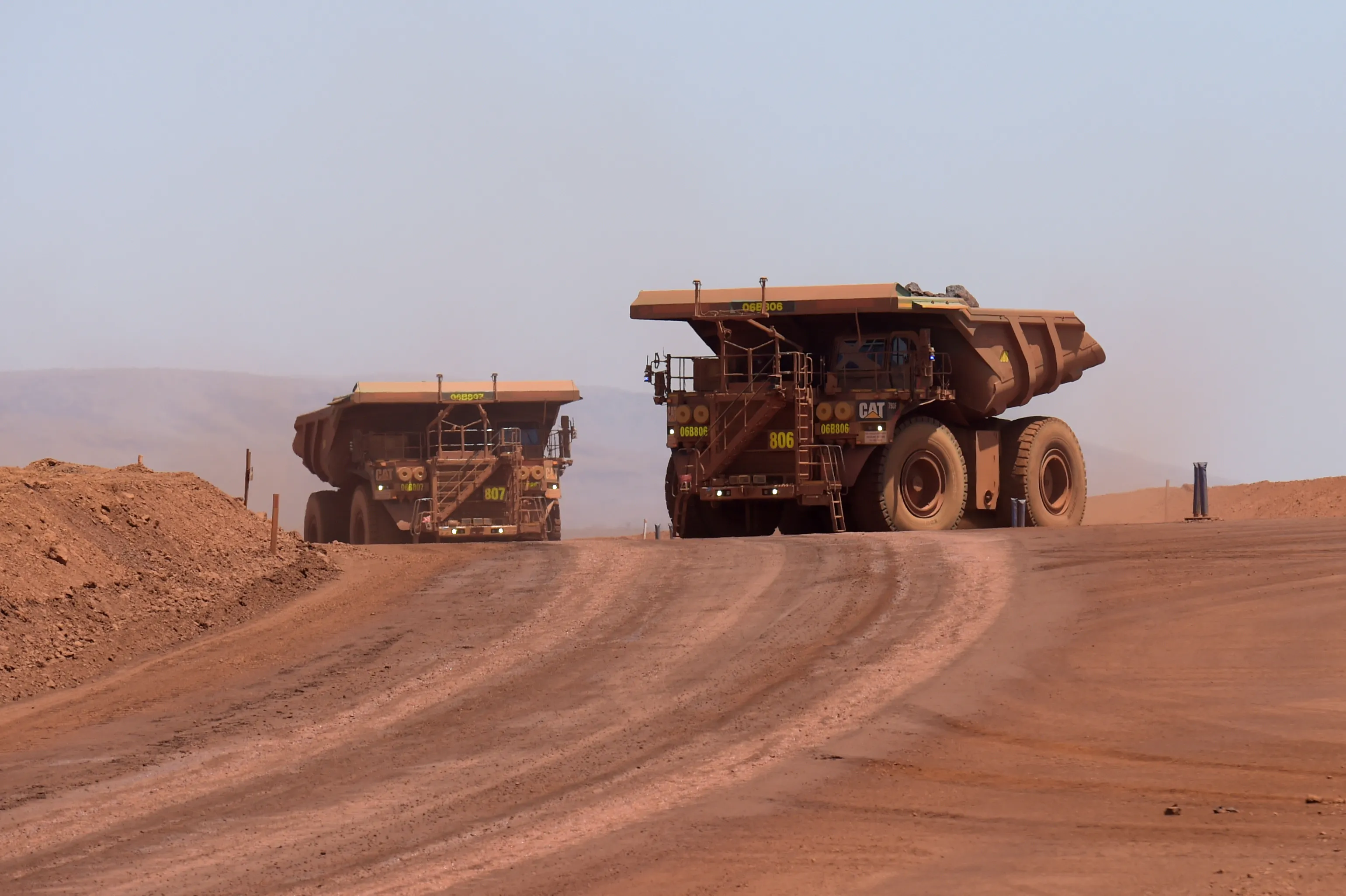 Autonomous haul trucks move along a haul road at an iron ore mine in Western Australia.