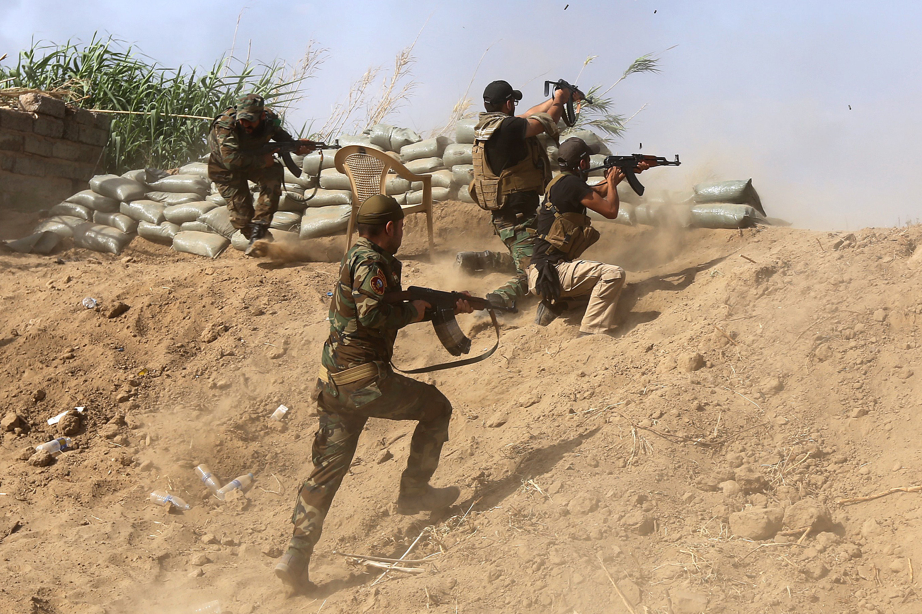 Iraqi Sunni fighters battling Islamic State jihadists fire their weapons on the outskirts of Iraq's Baiji oil refinery. Photographer: Ahmad Al-Rubaye/AFP via Getty Images
