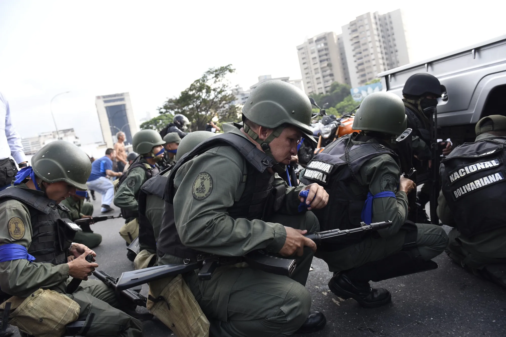 National Guard members supporting Venezuelan opposition leader Juan Guaido crouch for protection from gun fire on the Francisco Fajardo Highway during a military uprising in Caracas, Venezuela, on Tuesday, April 30, 2019.