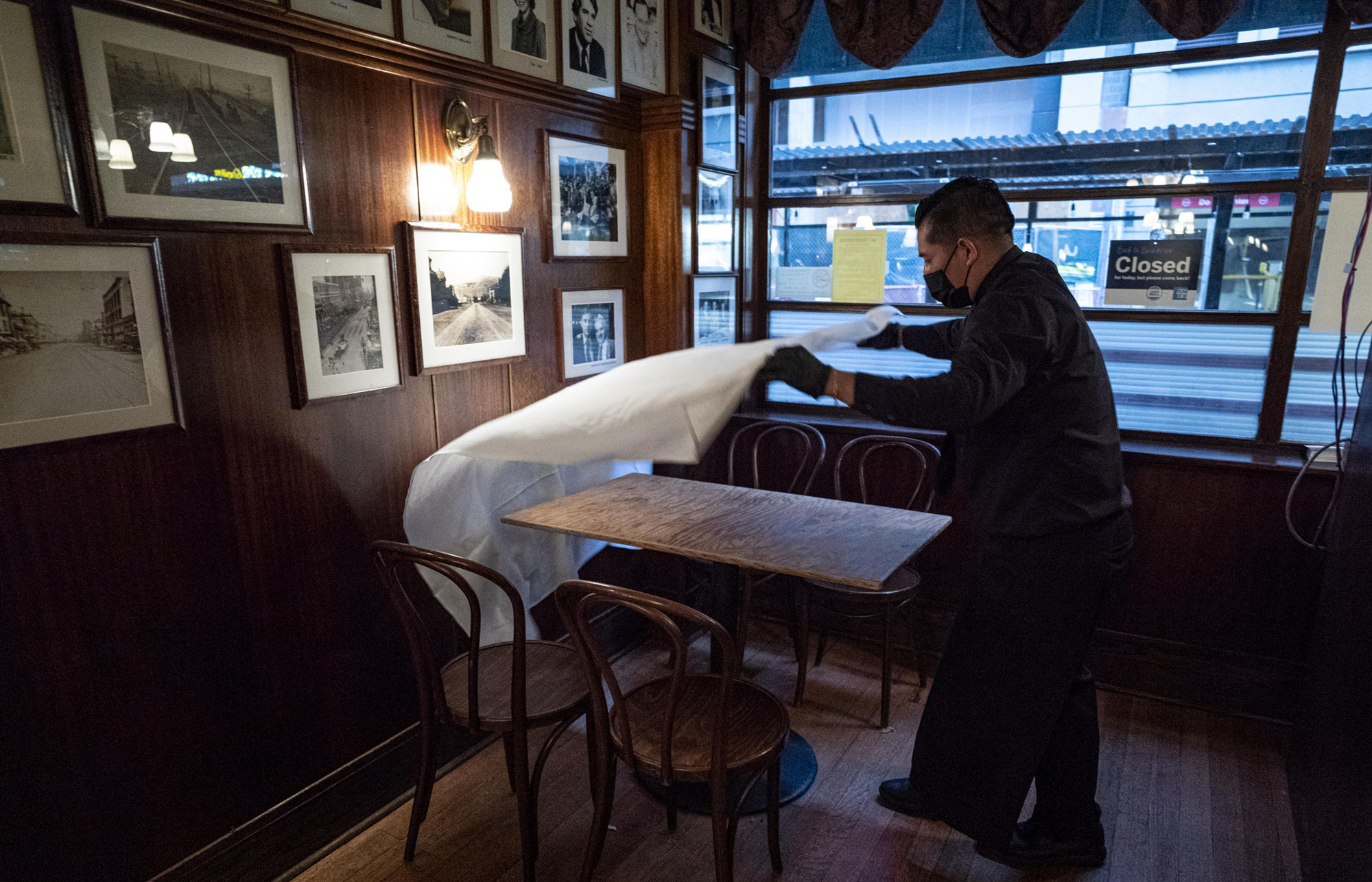 A worker puts down a table cloth at a restaurant in San Francisco.