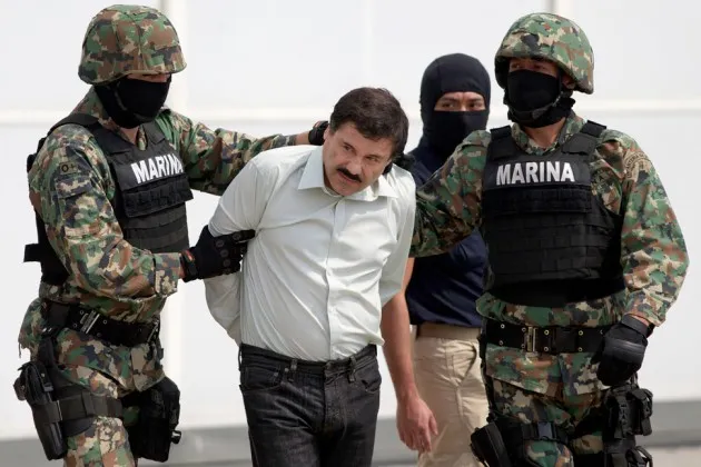 Joaquin “El Chapo” Guzman is escorted to a helicopter in handcuffs by Mexican navy marines at a hangar in Mexico City on Feb. 22