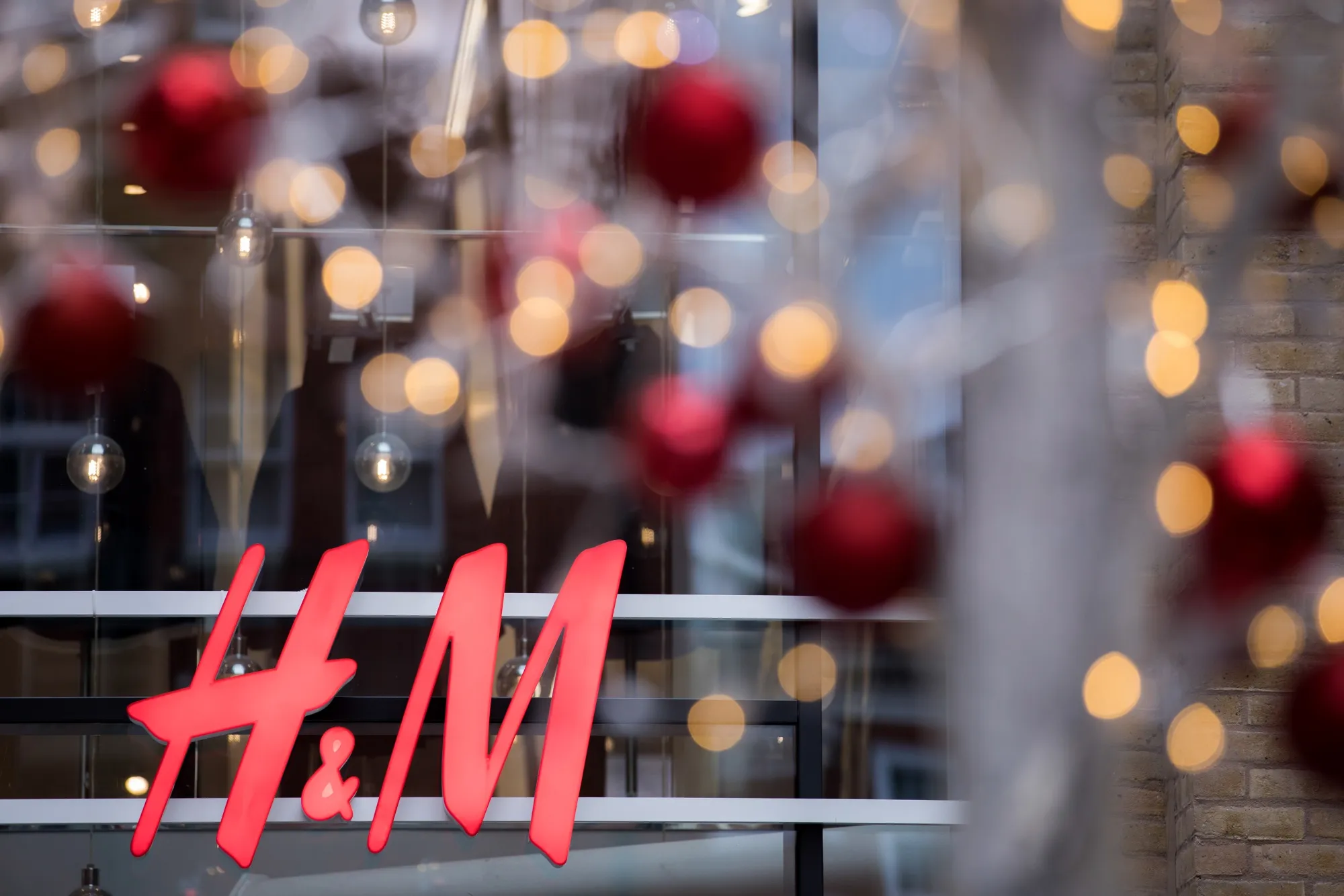 A sign sits on the front of a Hennes &amp; Mauritz AB clothing store in London.