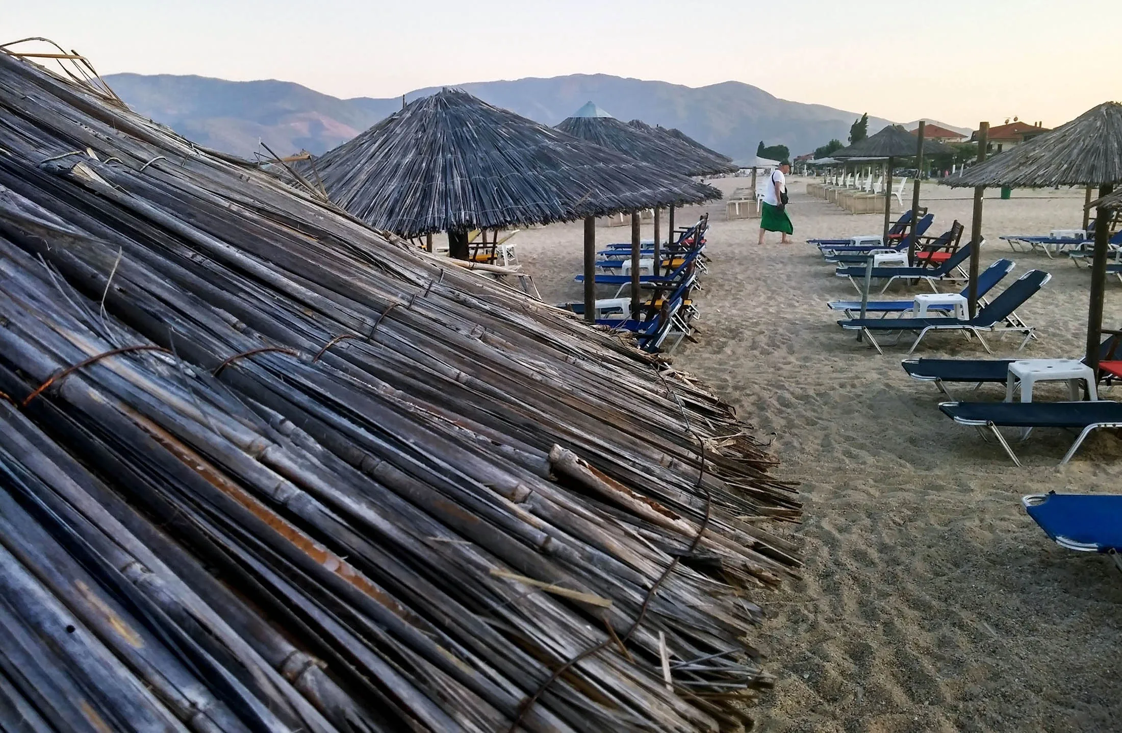 A holidaymaker passes rows of empty sunloungers and parasols on a beach at a tourist resort in Asprovalta, Greece, on Sunday, July 12, 2015. Tourism is the main source of earnings for debt-ravaged Greece, accounting for about 17 percent of the economy.
