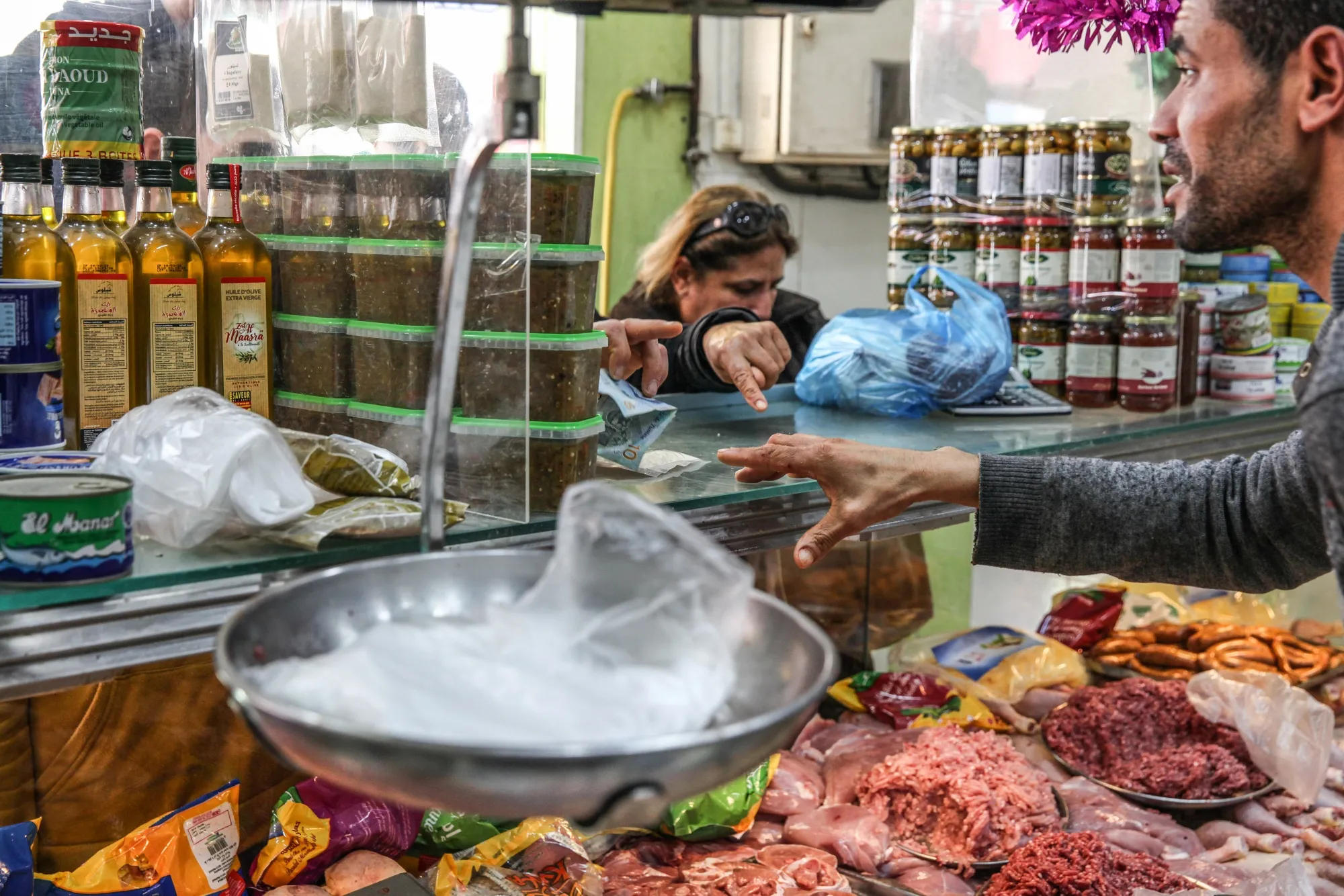 A customer hands over Tunisian dinar banknotes to a vendor for a purchase at a food shop in Tunis, Tunisia
