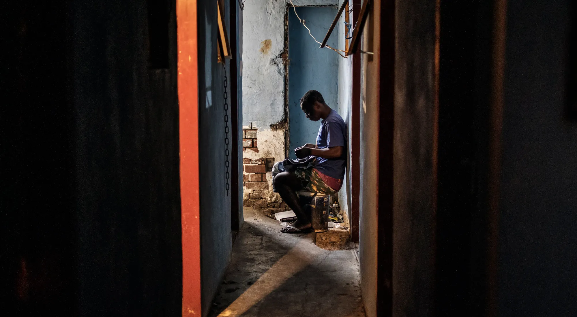 A foreign migrant mends his trousers inside a building in the Kwa Mai Mai area in Johannesburg.