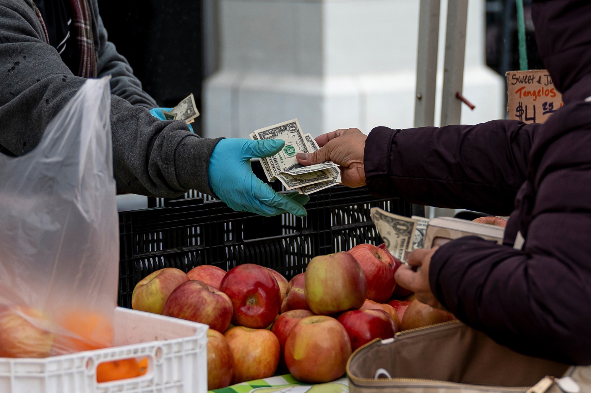 A shopper holds US banknotes while paying for produce at the farmer's market in San Francisco.