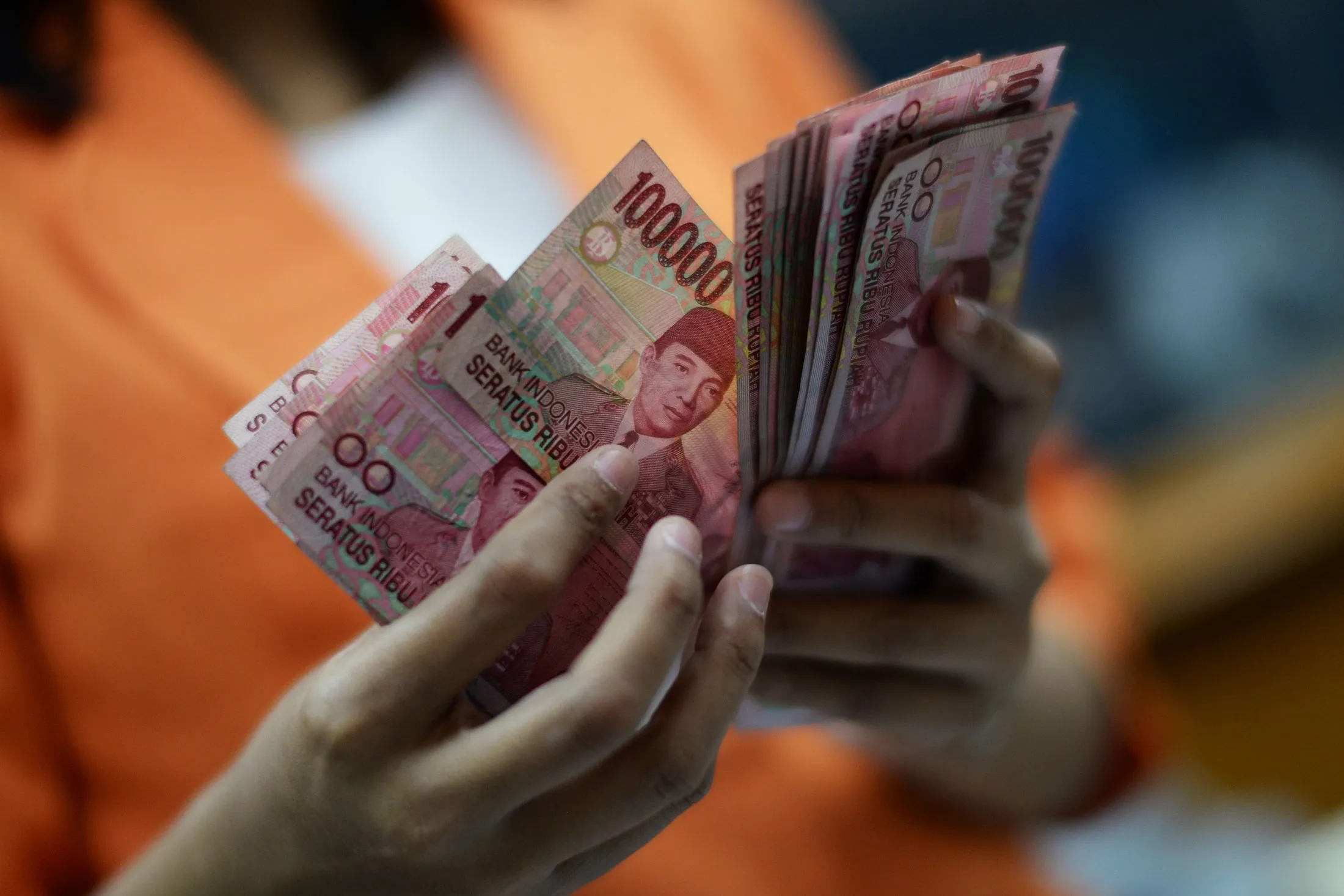 A clerk counts Indonesian 100,000 rupiah banknotes for a photograph at a currency exchange office in Jakarta, Indonesia, on Wednesday, Sept. 9, 2015.
