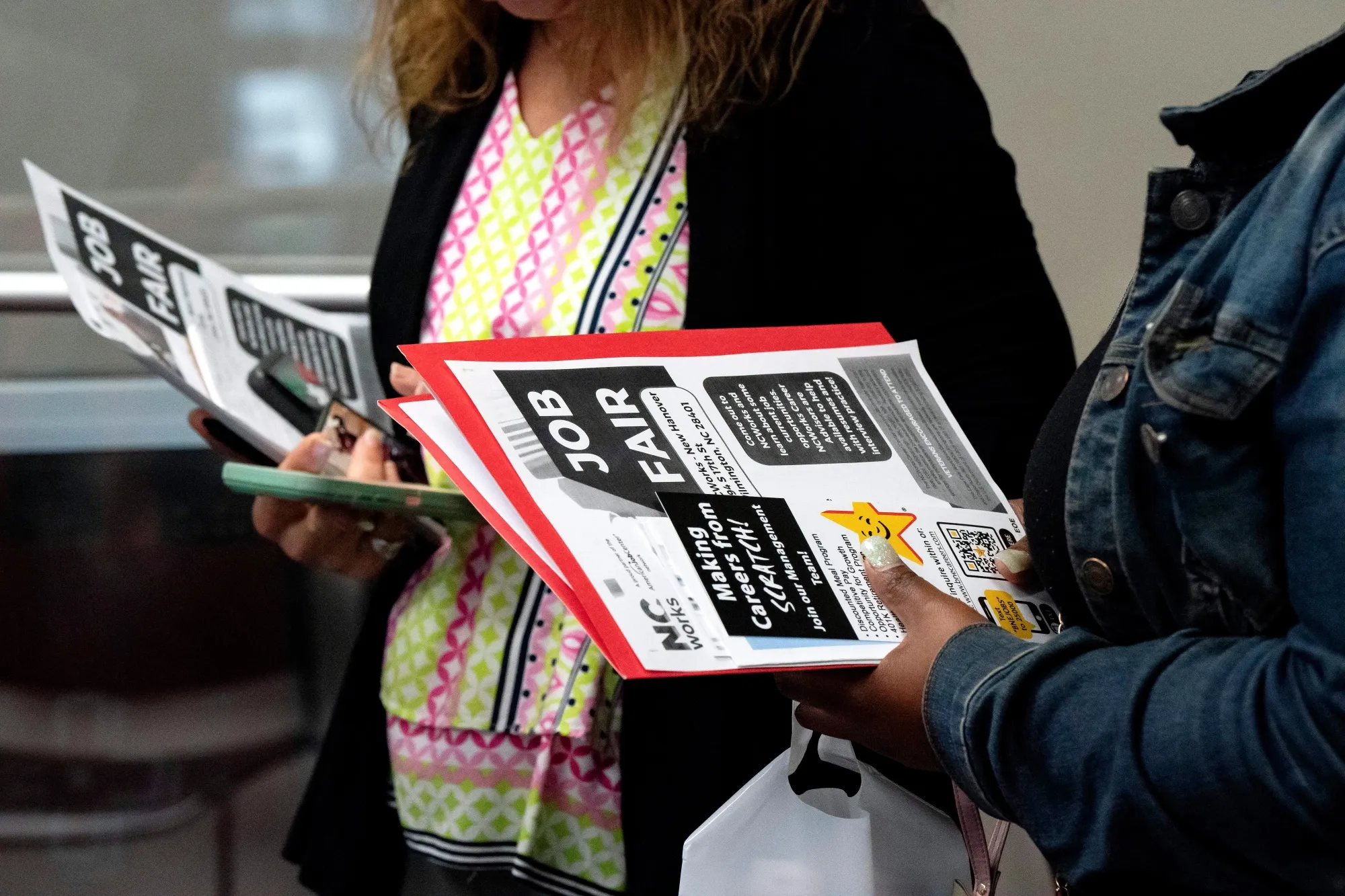 Jobseekers hold flyers during a career fair.