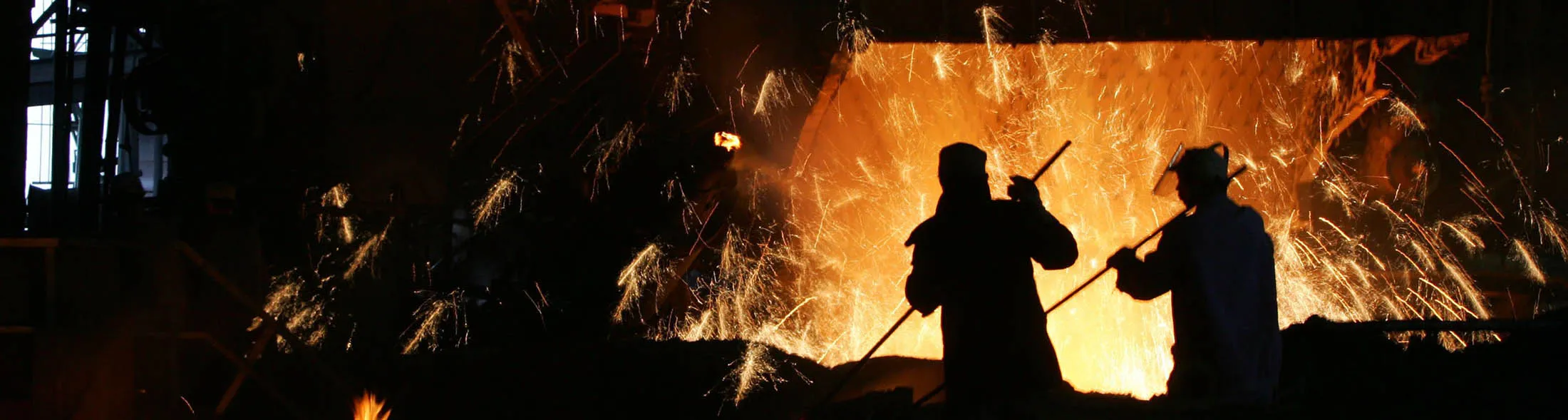 Steelworkers stir material in front of a steel making furnace in China.
