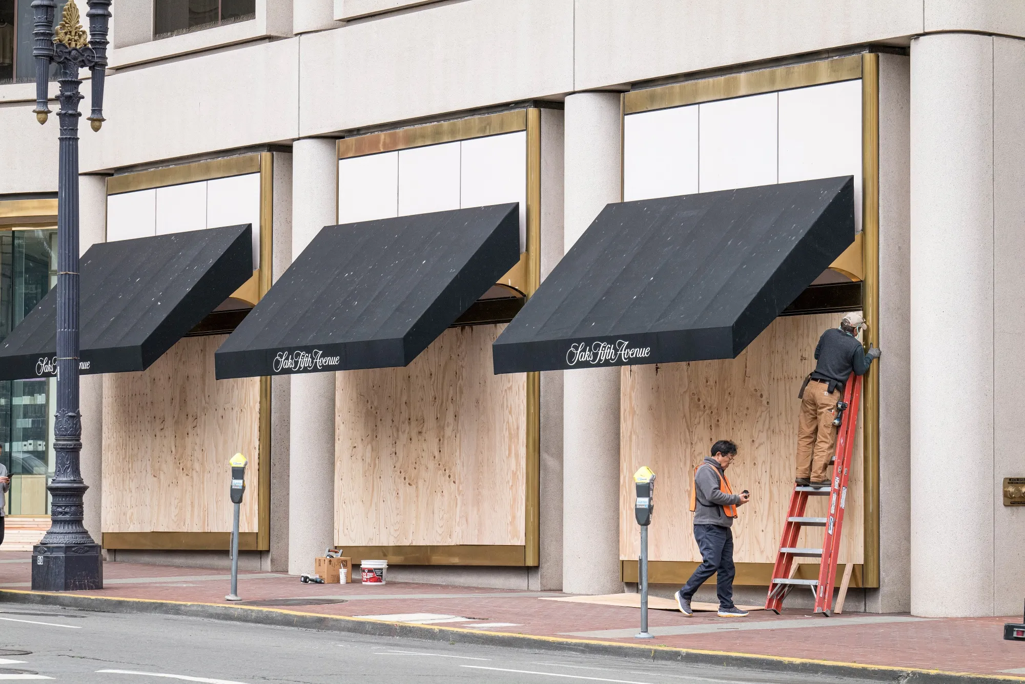Workers install wood panels over windows of a Saks Fifth Avenue store in San Francisco, California.