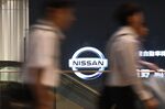 People walk past a screen playing a Nissan Motor Co. promotional video at the company's headquarters in Yokohama.