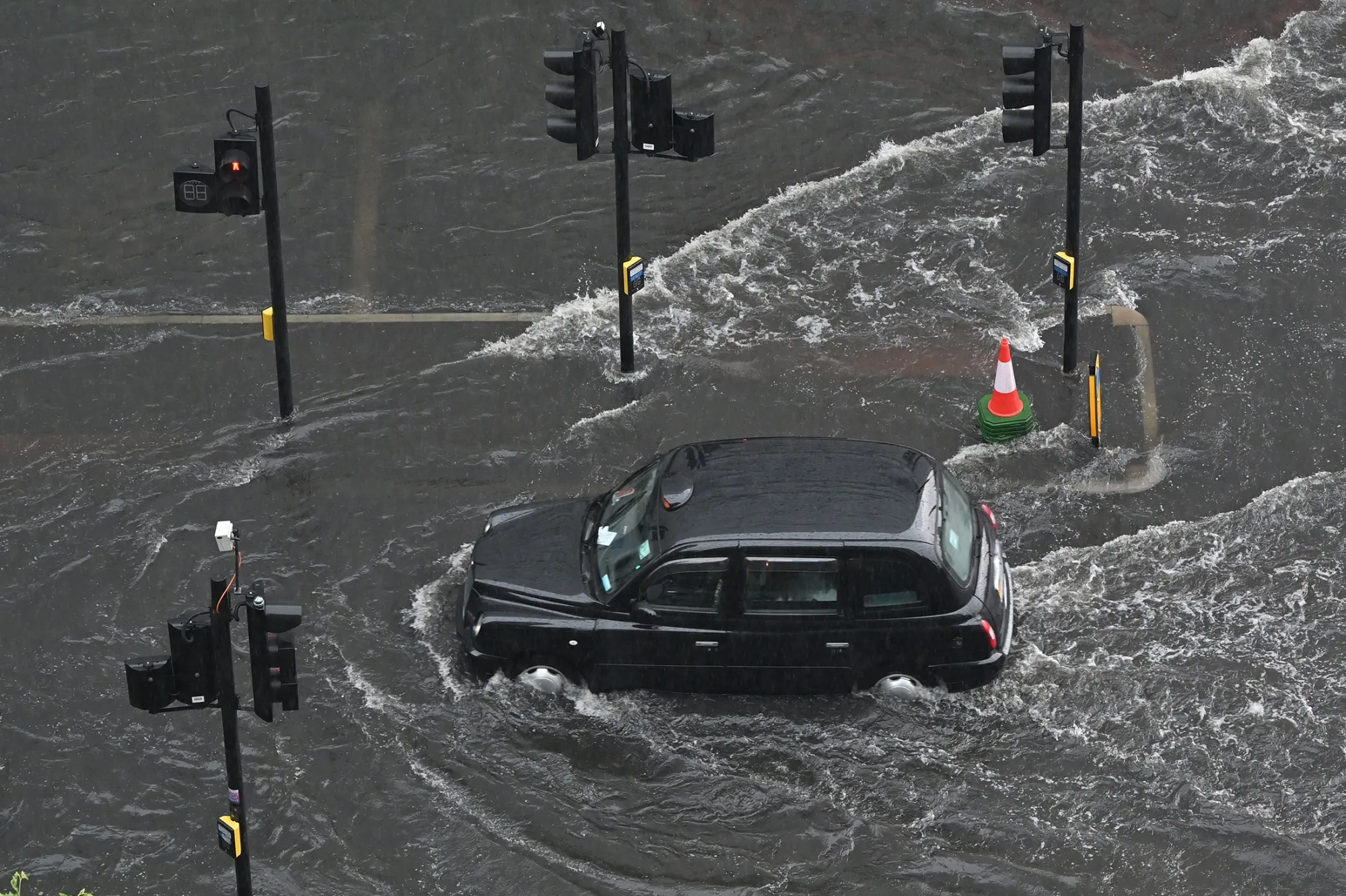 A London taxi drives through a flooded road in The Nine Elms district of London in July 2021.