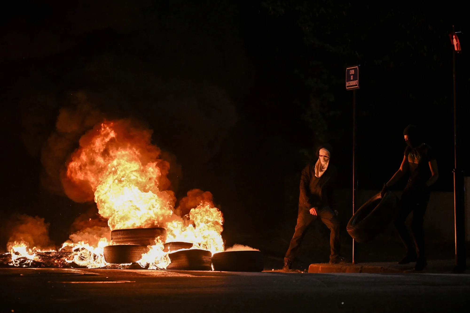 People throw tires on a fire blocking a street in Bordeaux, France on June 29.
