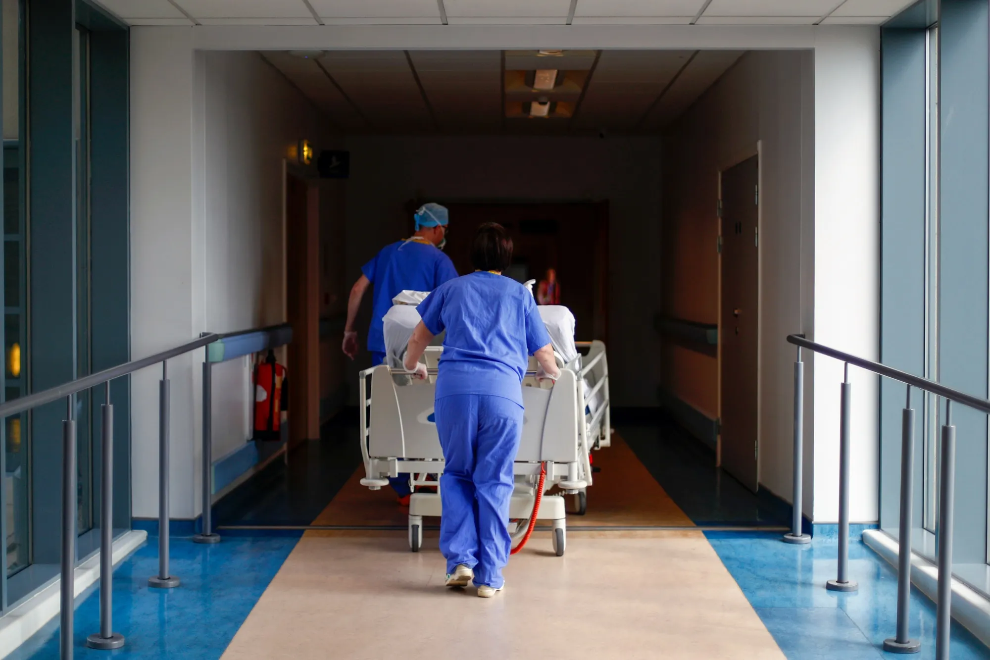 Medical staff transfer a patient along a corridor at a healthcare clinic in Blackburn, UK.