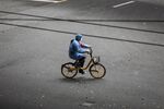 A worker in personal protective equipment rides a bike along a road during a lockdown due to Covid-19 in Shanghai.