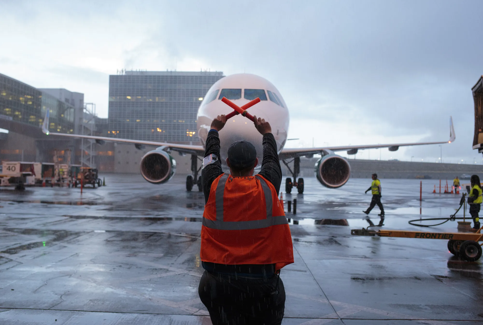 A ground operations employee directs an airplane plane to a gate at Denver International Airport in Colorado.&nbsp;