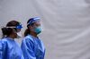 Medical staff wear personal protective equipment (PPE) kits, including facemasks and shields, as they walk near the rapid antigen coronavirus testing site at Hard Rock Stadium in Miami Gardens near Miami, on August 5, 2020.