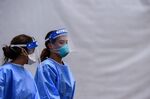 Medical staff wear personal protective equipment (PPE) kits, including facemasks and shields, as they walk near the rapid antigen coronavirus testing site at Hard Rock Stadium in Miami Gardens near Miami, on August 5, 2020.