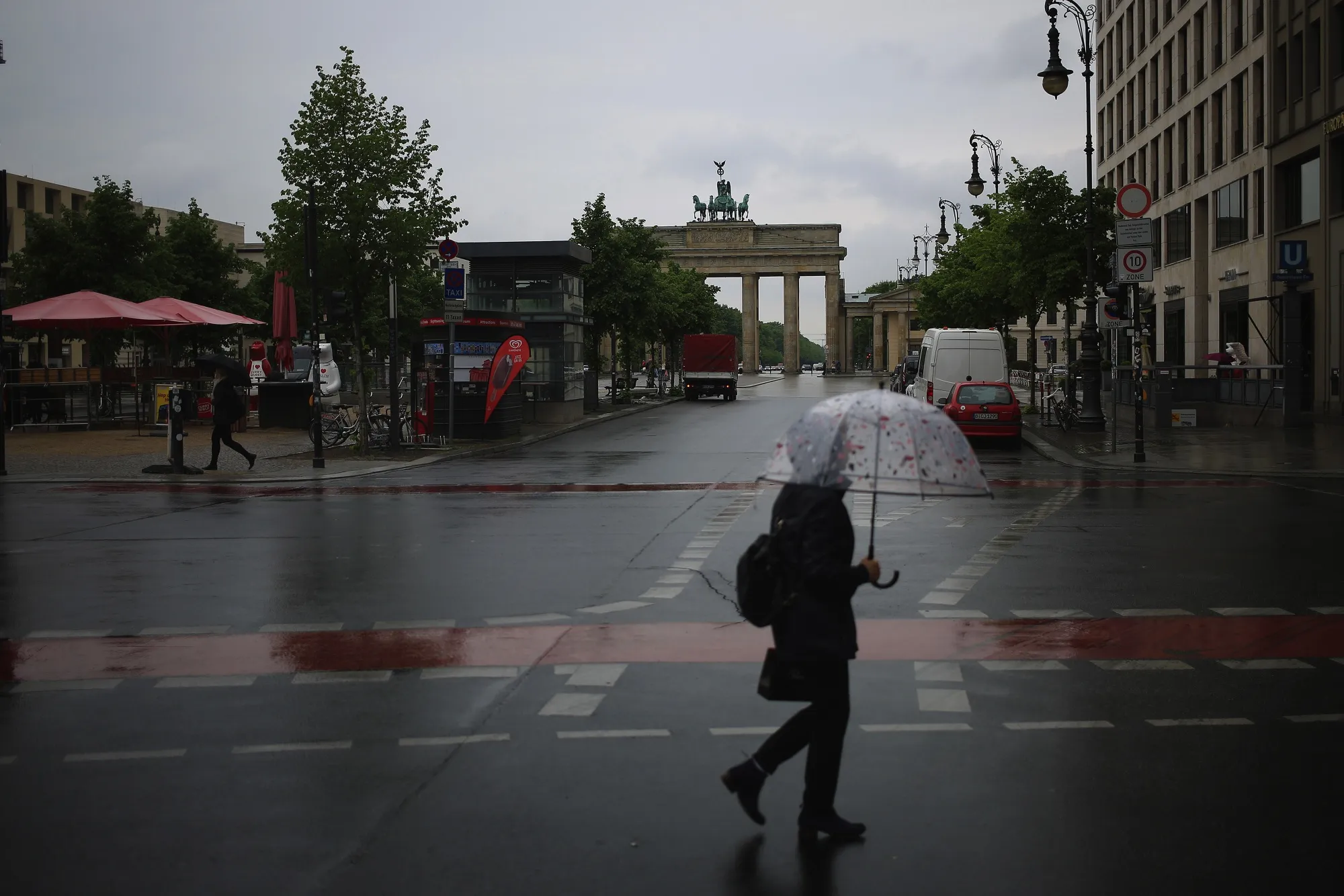 A pedestrian shelters under an umbrella while crossing Unter den Linden boulevard near the Brandenburg Gate monument in Berlin on May 4.