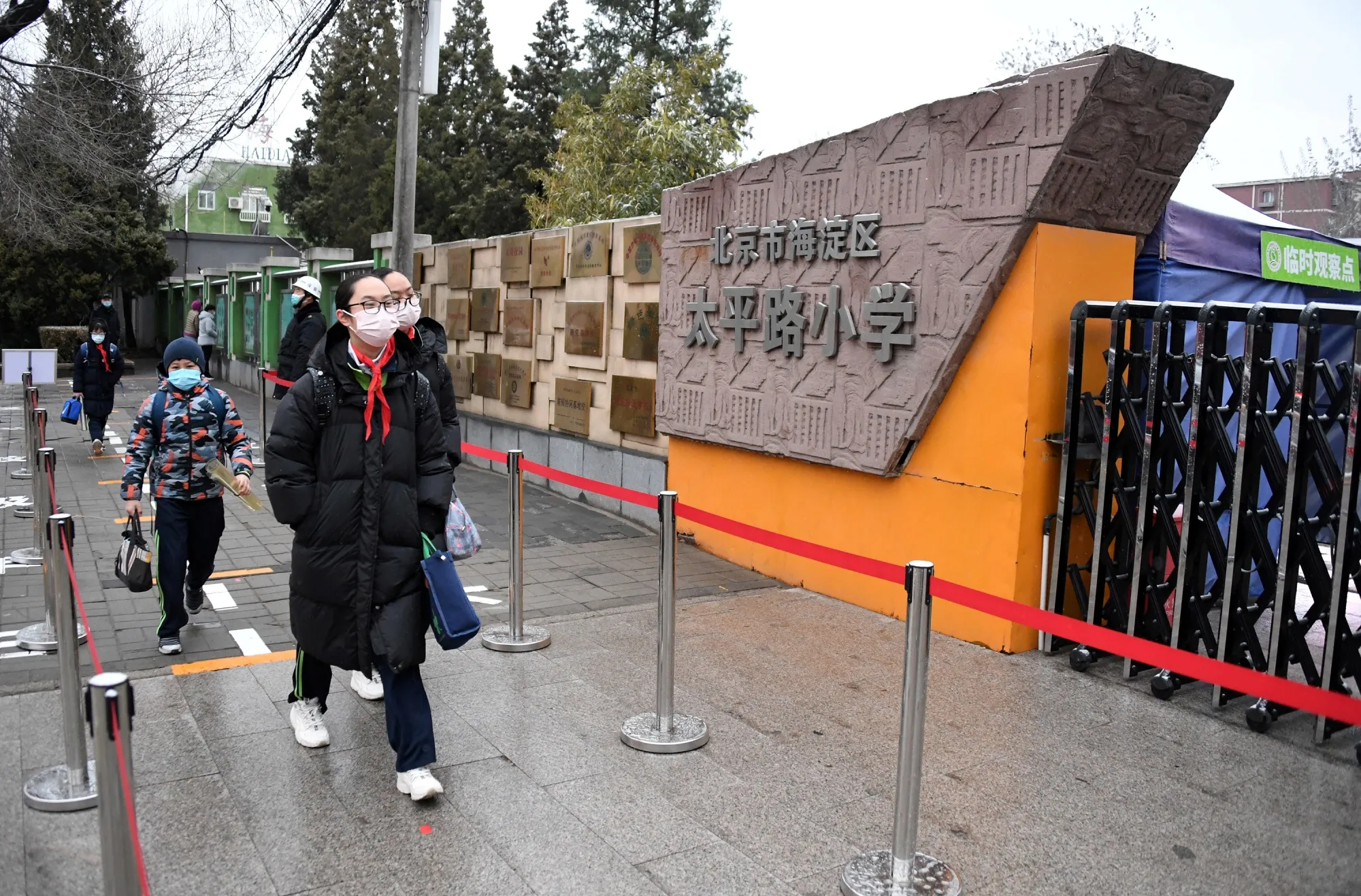 Students walk into the campus of a primary school in the Haidian District of Beijing.