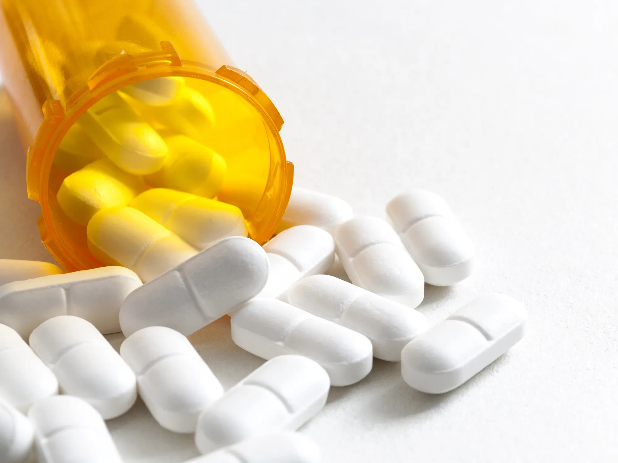 Hydrocodone capsules spilling out of a prescription bottle with copyspace